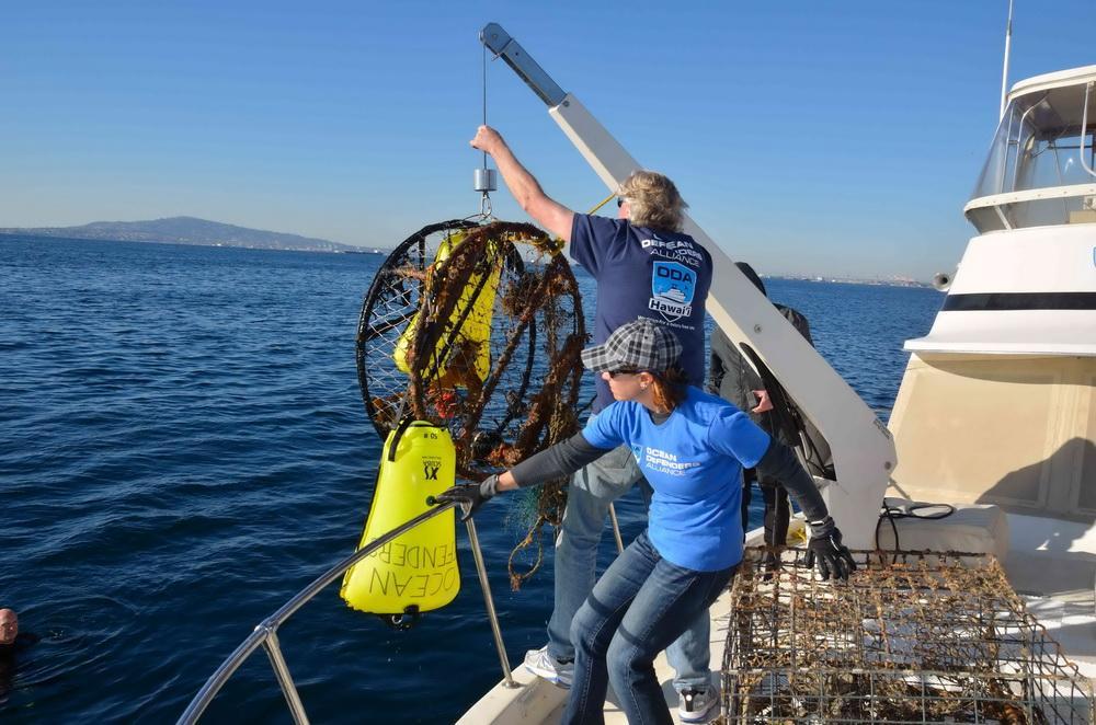 ODA Volunteers pull abandoned crab trap onto boat deck for proper disposal.